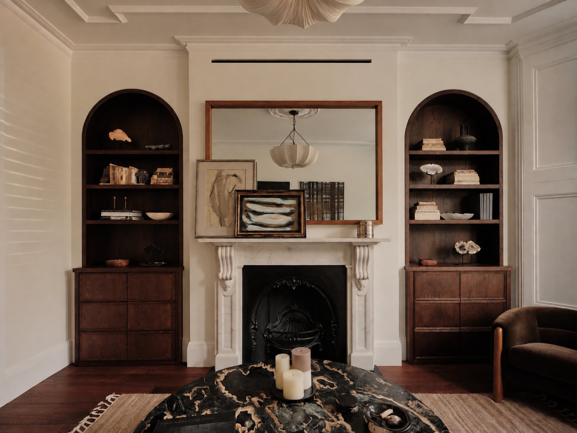 A finished period drawing room with a marble chimneypiece, arched joinery and decorated walls